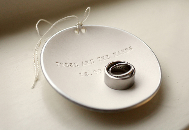 wedding bands sit on keepsake ornament engraved with words, "These are the hands"