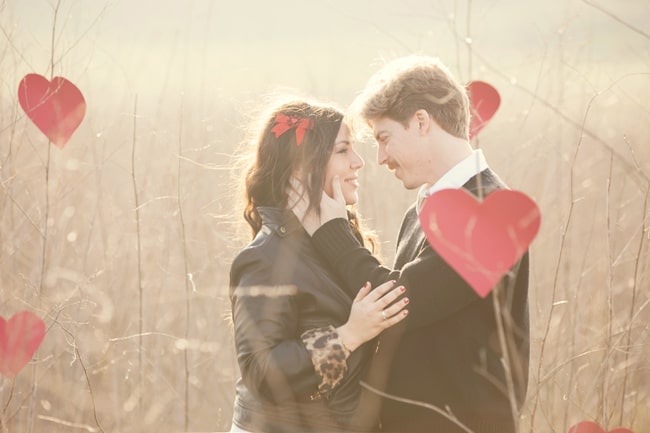 couple in field with red paper hearts