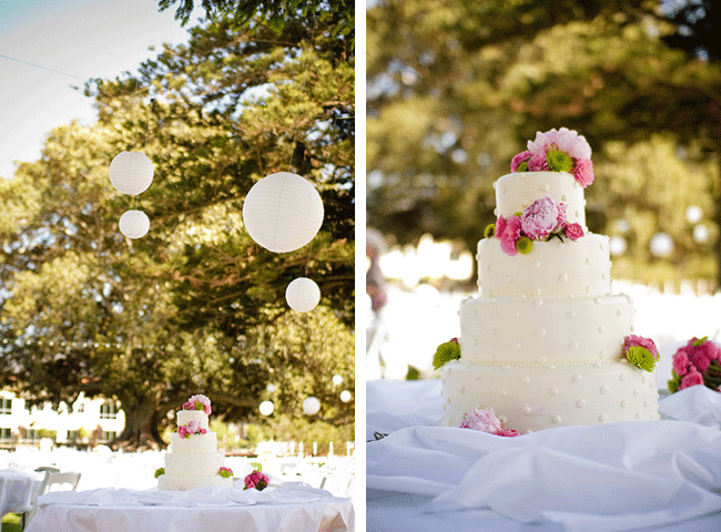 white lanterns hang above 4-tier white dot cake with pink flowers on top