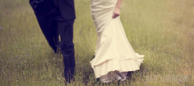 bride and groom walk in the grass