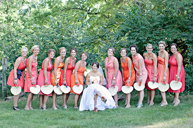 bridesmaids in mismatched coral dresses carrying fans
