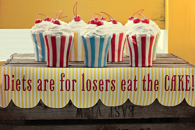 white, red, blue, and yellow striped cupcakes with cherry on top