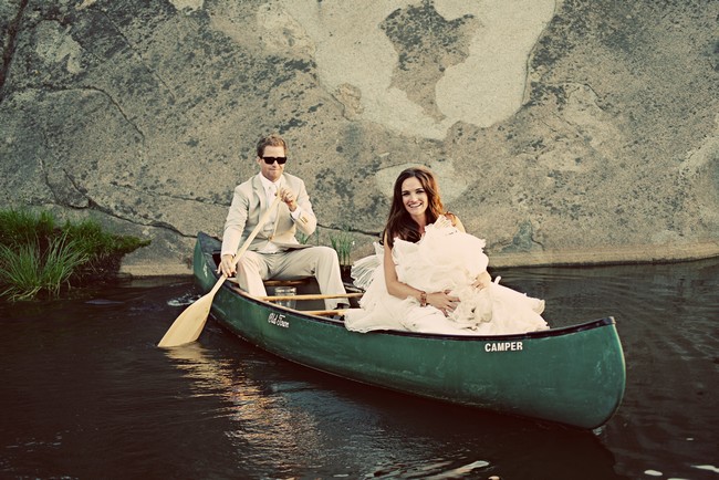 bride and groom in canoe paddling along lake