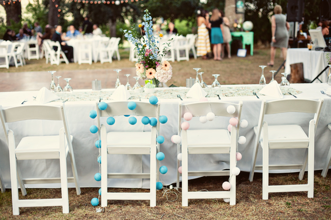 Bride and groom folding white chairs with blue and pink styrofoam ball garland decor around chair. Wedding at Highland Springs Resort.