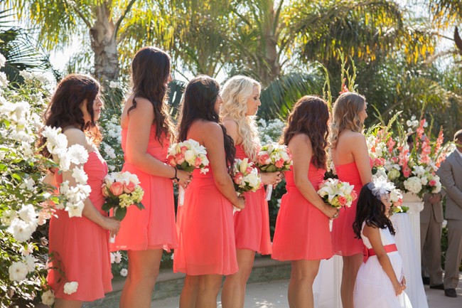 brides maids wearing coral dresses holding tropical flowers