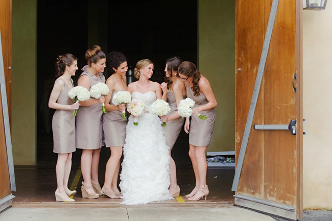 bride with bridesmaids stading infront of barn door at montaluce winery