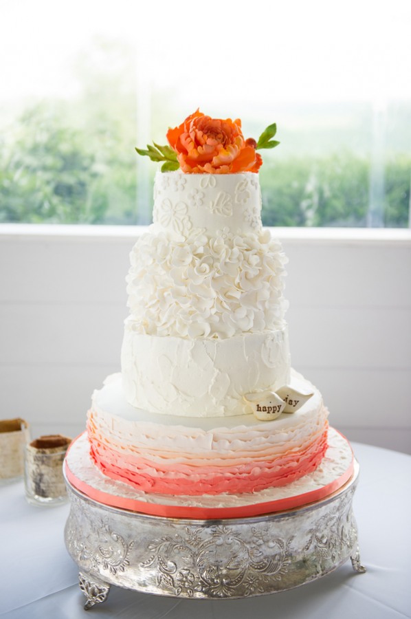 white wedding cake with peach base and orange flower on top