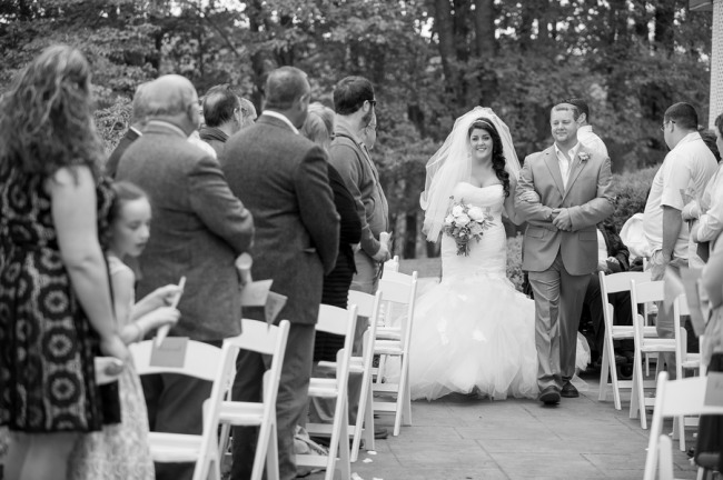black and white photo of bride walking down the aisle