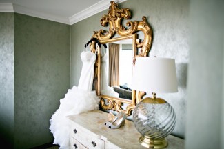 Wedding dress hanging on gold framed mirror