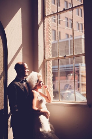 bride and groom stading near window