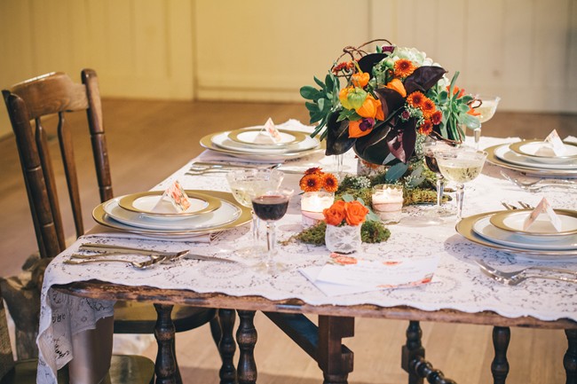 Lace tablescape with moss, vintage keys, succulents and orange flowers in front of a fire place