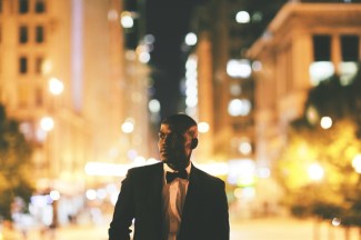 Man standing outside on a Chicago street wearing a tux looking off into the distance