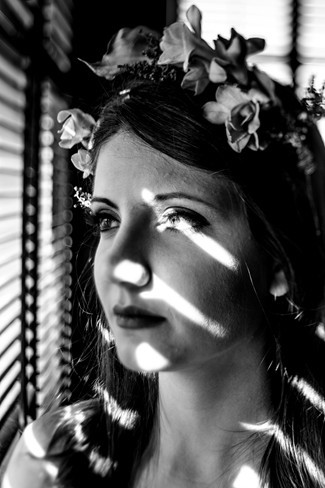 25 bride looking out blinds with a shadow on her face wearing flower crown