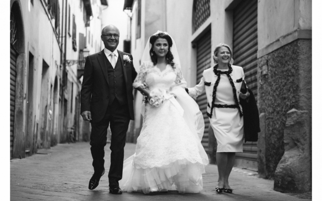 black and white photo of bride and her parents walking through street of florence to church