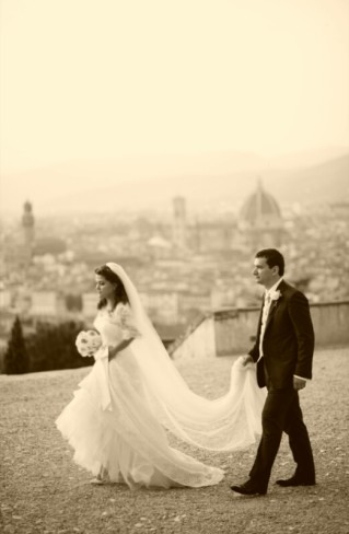 bride and groom walking with florence city scape in the background. Groom holding brides train