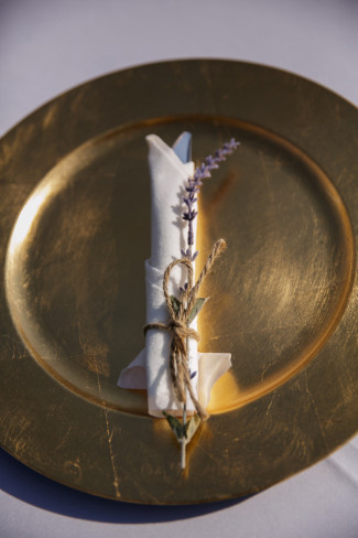lavender sprig and napkin wrapped in twine on gold charger