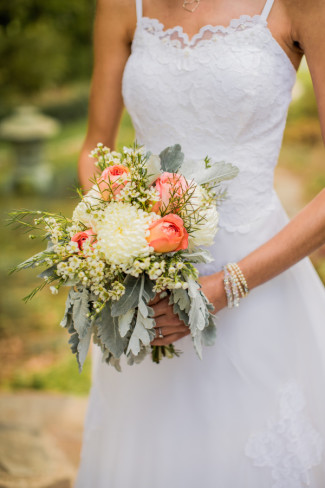 Bride holding bouquet of Dusty Miller, China Mums, Wax flower, and peach roses