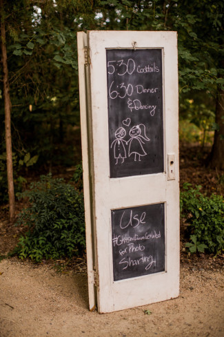 white door standing in woods with wedding times written in chalk