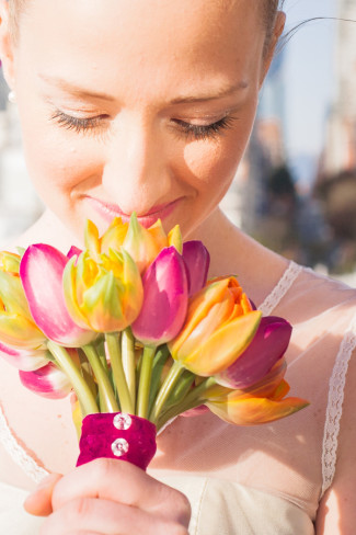 smelling bouquet of pink, orange, and yellow tulips