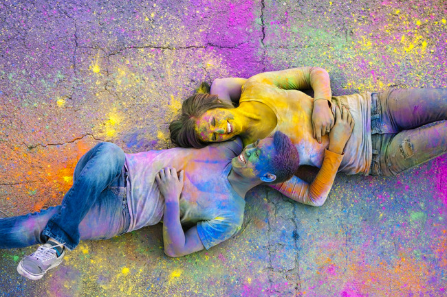 A couple lying on the cement after a holi powder fight for engagement session 