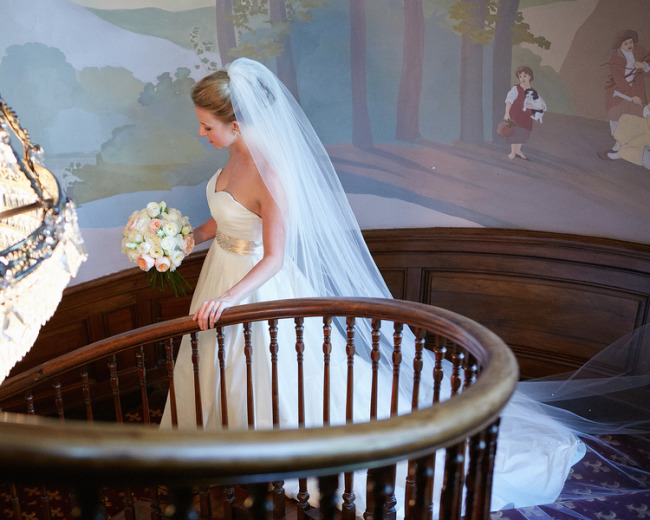 Bride walking down the stairs in a long chapel length veil at Tate House Mansion 
