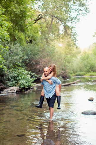 Man carrying women on his back through a stream for an engagement shoot