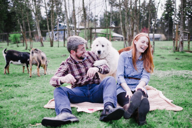 Dog trying to jump on couples lap during outdoor engagement shoot picnic