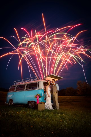 Bride and groom standing in front of blue van watching fireworks by Pyrotex