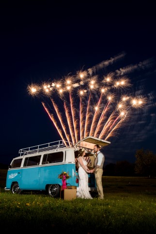 Bride and groom standing in front of blue van watching fireworks by Pyrotex