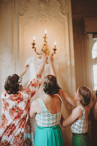 bridesmaids pulling down a Sottero & Midgley gown from the wall sconce