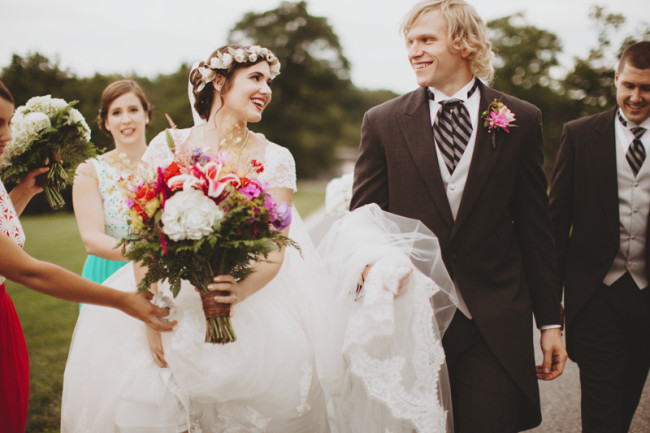 Groom carrying brides veil and dress after wedding ceremony
