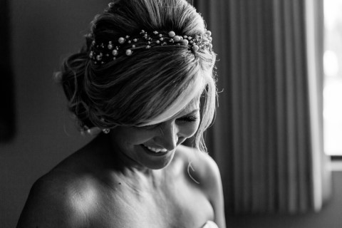 Black and white photo of bride looking down wearing a basic pearl head band