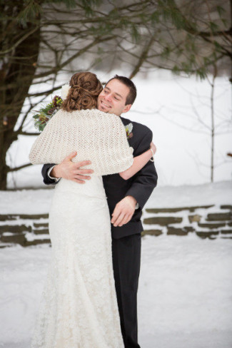 bride in knit shawl hugs her groom