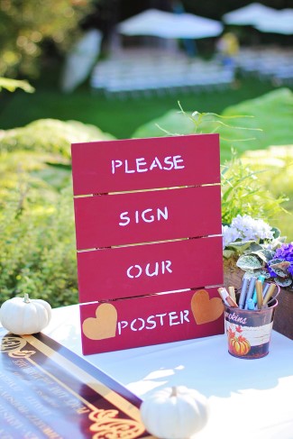 Red wooden sign asking wedding guests to sign the poster