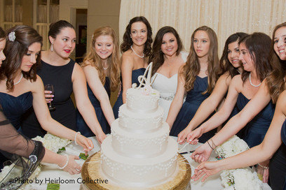 Bride with her bridesmaids about to pull charms from the wedding cake in a traditional wedding cake pull 