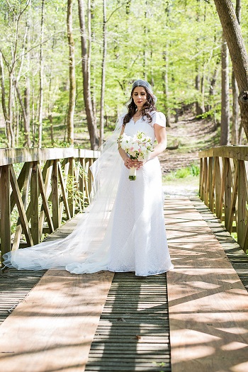 Bride wearing downton abbey inspired bridal outfit standing on bridge