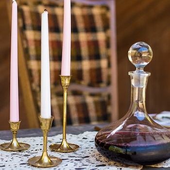 Vintage brass candle holder with lace table runner and decanter on wedding reception table