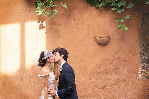 bride and groom kissing infront of a teracotta wall