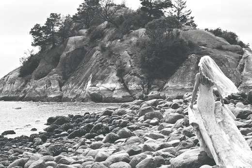 Black and white photo of bride walking on the beach