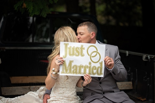 Bride and groom kissing holding a just married sign