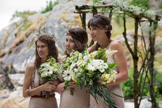 Bridesmaids standing together on beach for wedding ceremony wearing boho outfits