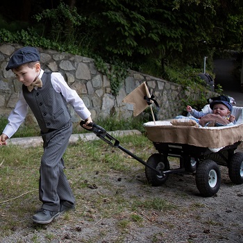 Ring bearer pulling baby in a rustic themed burlap wagon