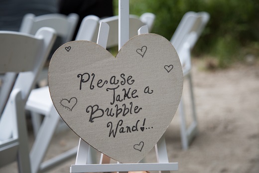 Wedding sign in the shape of a heart asking guest to take bubbles