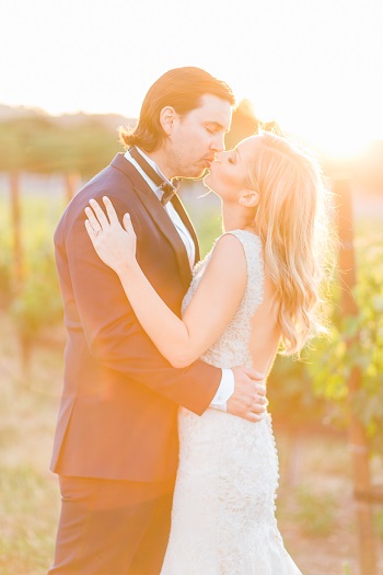 Bride and groom kissing in vineyard captured by Kaitie Brainerd Photography
