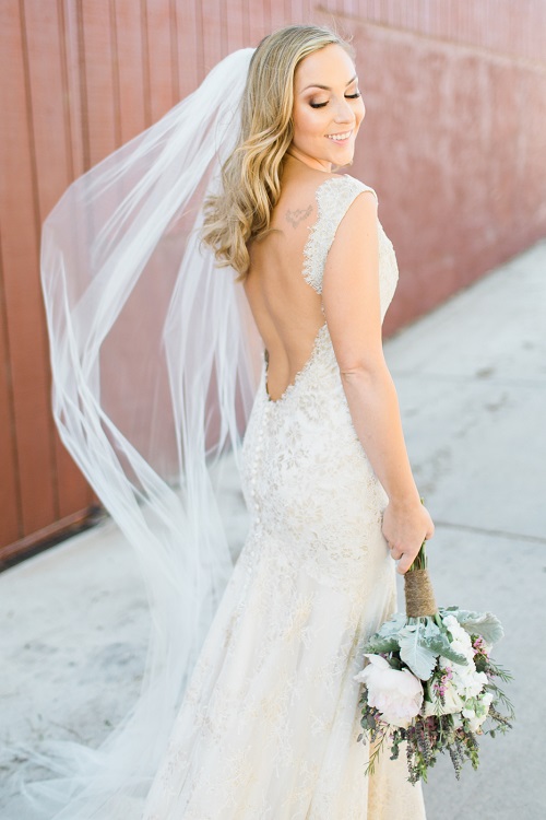 Bride posing in a floor length veil holding a bridal bouquet with rustic flair