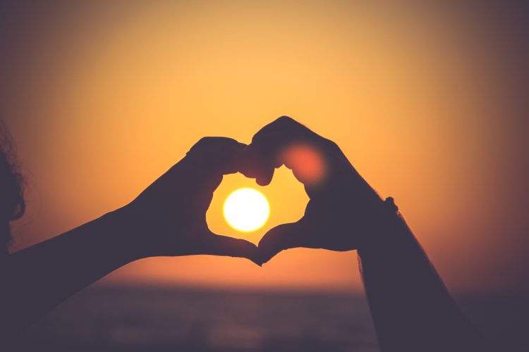 hands in heart shape with sunset in middle