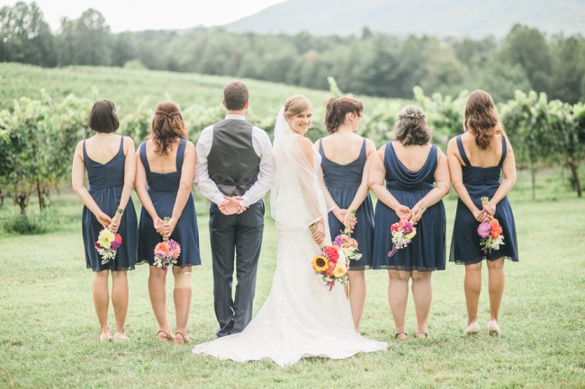 bridal party in vineyard with bride looking over shoulder