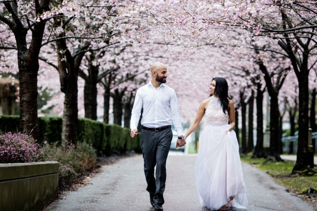 cherry blossom engagement shoot couple walk on Vancouver sidewalk