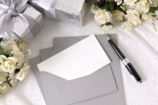 blank bröllopsinbjudan med kuvert som läggs på brud spets med flera bröllopsgåvor