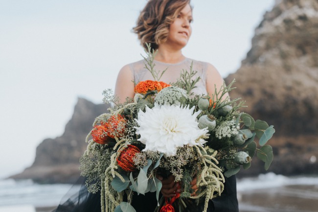 bride holds large bouquet on beach